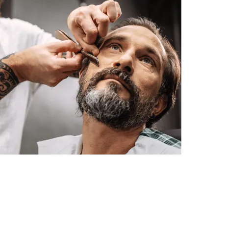 Barbiere che rifinisce la barba con il rasoio
