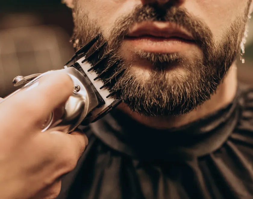 Barbiere che rifinisce barba e capelli con la macchinetta